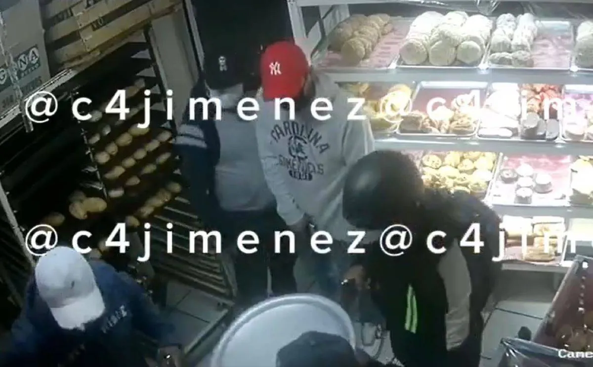 En un video que subió a sus redes sociales Carlos C4Jiménez, se puede observar a un señor que se encuentra escogiendo sus bizcochos, cuando dos, primeros sujetos, con gorra, sudadera y cubrebocas entran con arma en mano. Foto: Captura