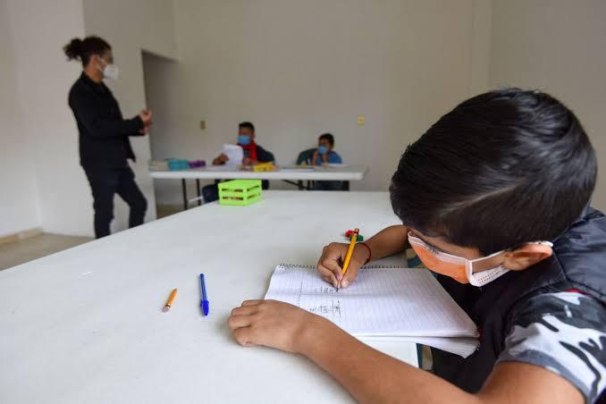 niño dibujando con cubrebocas en escuela particular guardando sana distancia