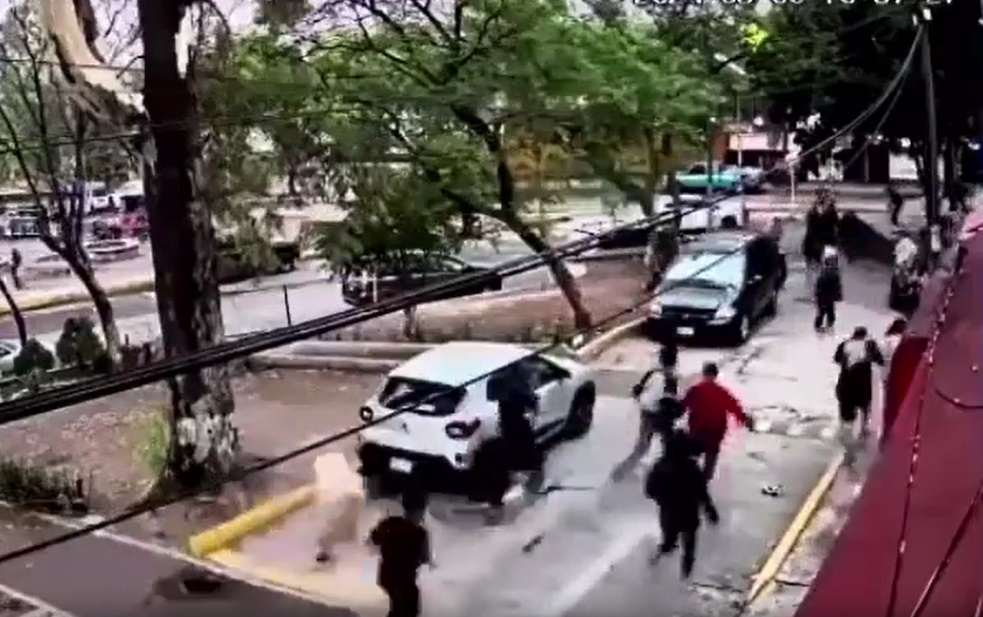 Estudiantes del CCH Naucalpan tratan de escapar, del ataque por porros, cruzando un estacionamiento. Foto: Captura.